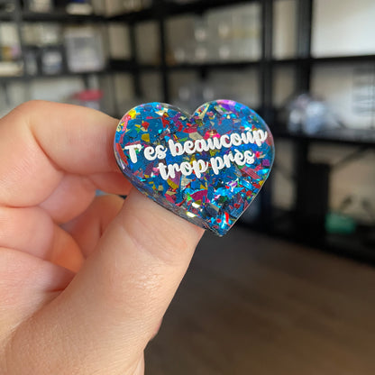 [CONTRÔLE TECHNIQUE] Broche "T'es beaucoup trop près" en acrylique transparente avec des éclats de confettis bleus et multicolores
