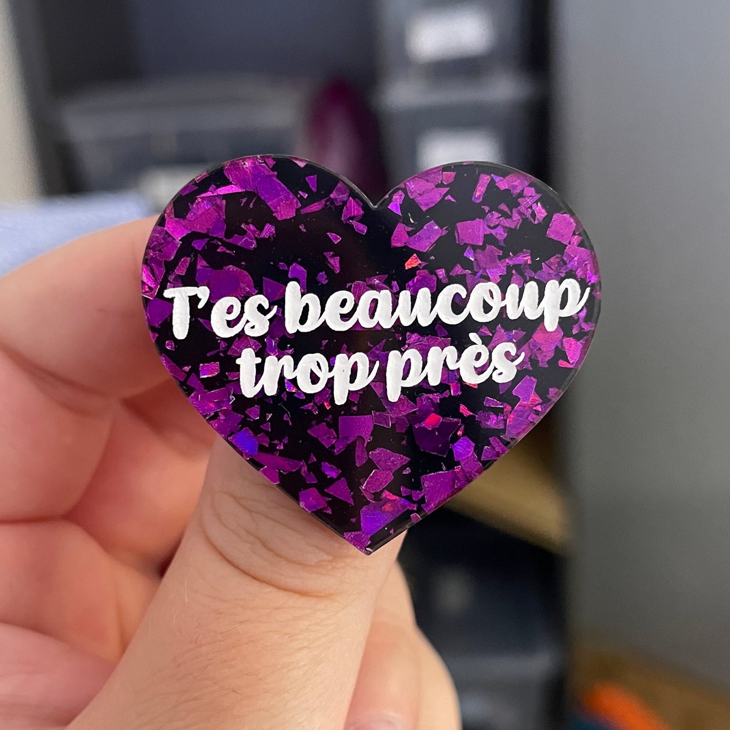 Broche "T'es beaucoup trop près" en noire avec des éclats de confettis violets