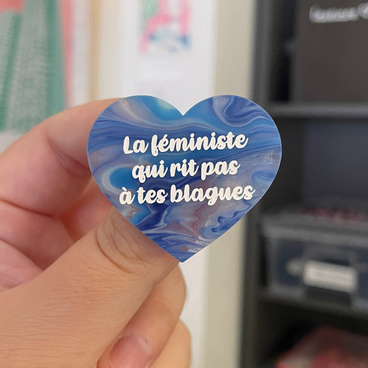 Broche "La féministe qui rit pas à tes blagues" en acrylique semi transparente marbrée bleue et blanche