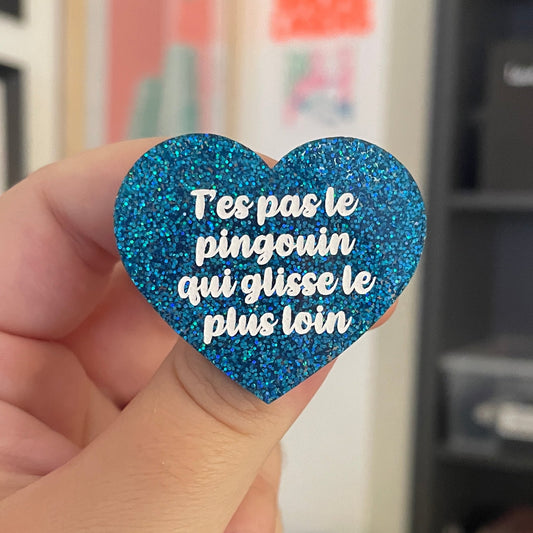 Broche "T'es pas le pingouin qui glisse le plus loin" en acrylique à paillettes bleues holographiques