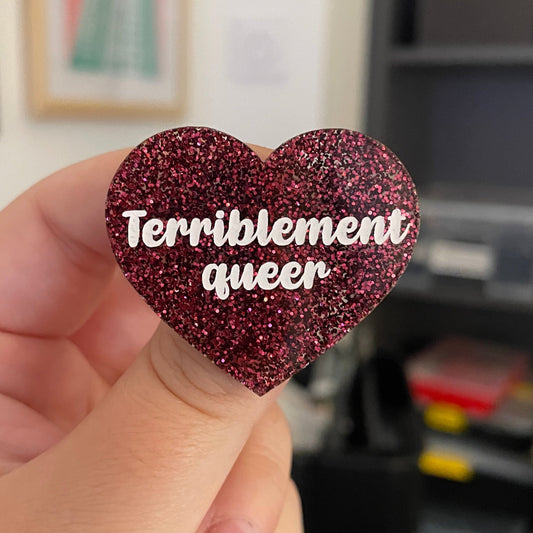 [CONTRÔLE TECHNIQUE] Broche "Terriblement queer" en acrylique à paillettes bordeaux