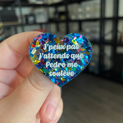 Broche "J'peux pas j'attends que Pedro me soulève" en acrylique transparente avec des éclats de confettis bleus et multicolores