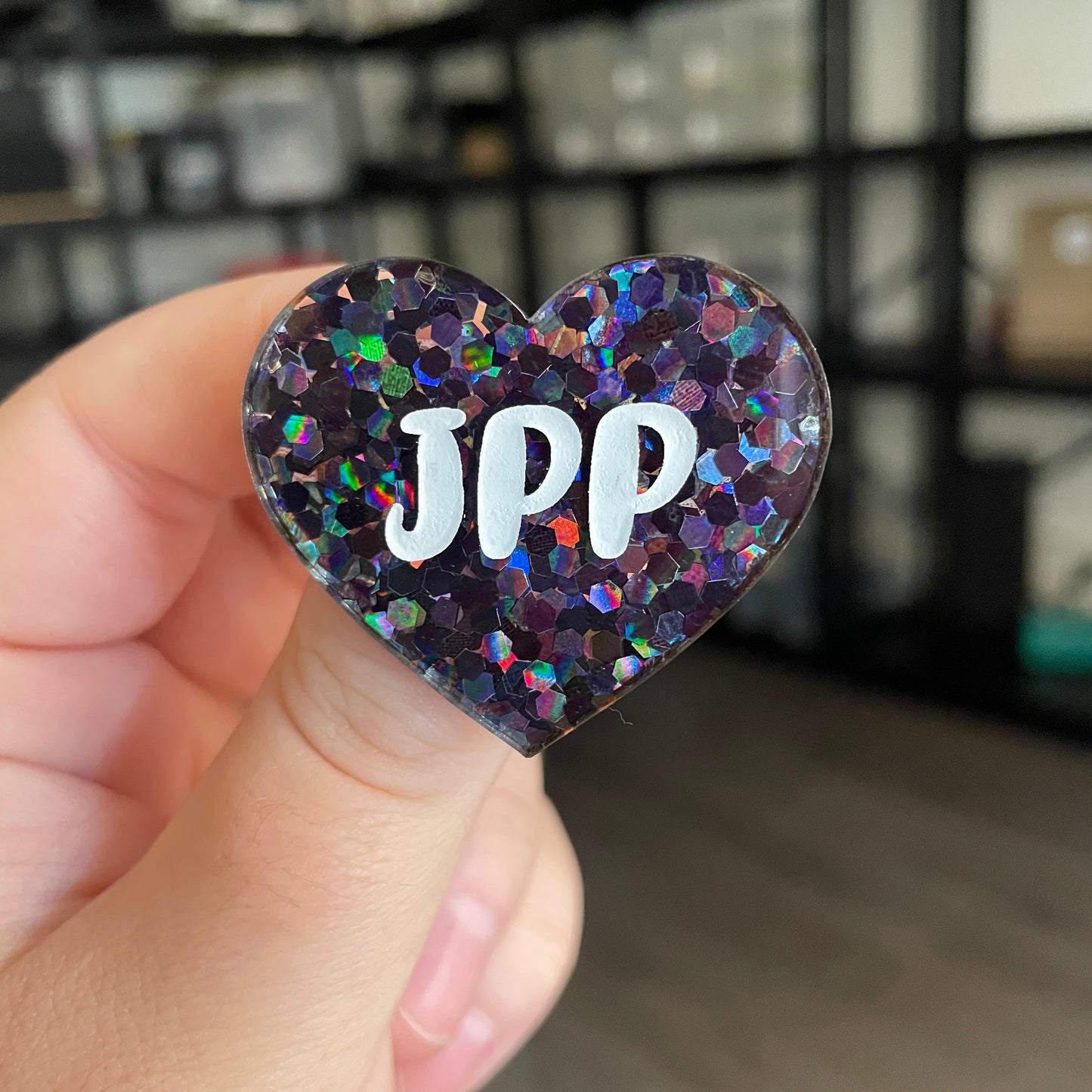 Broche "JPP" en acrylique semi transparente à confettis noirs