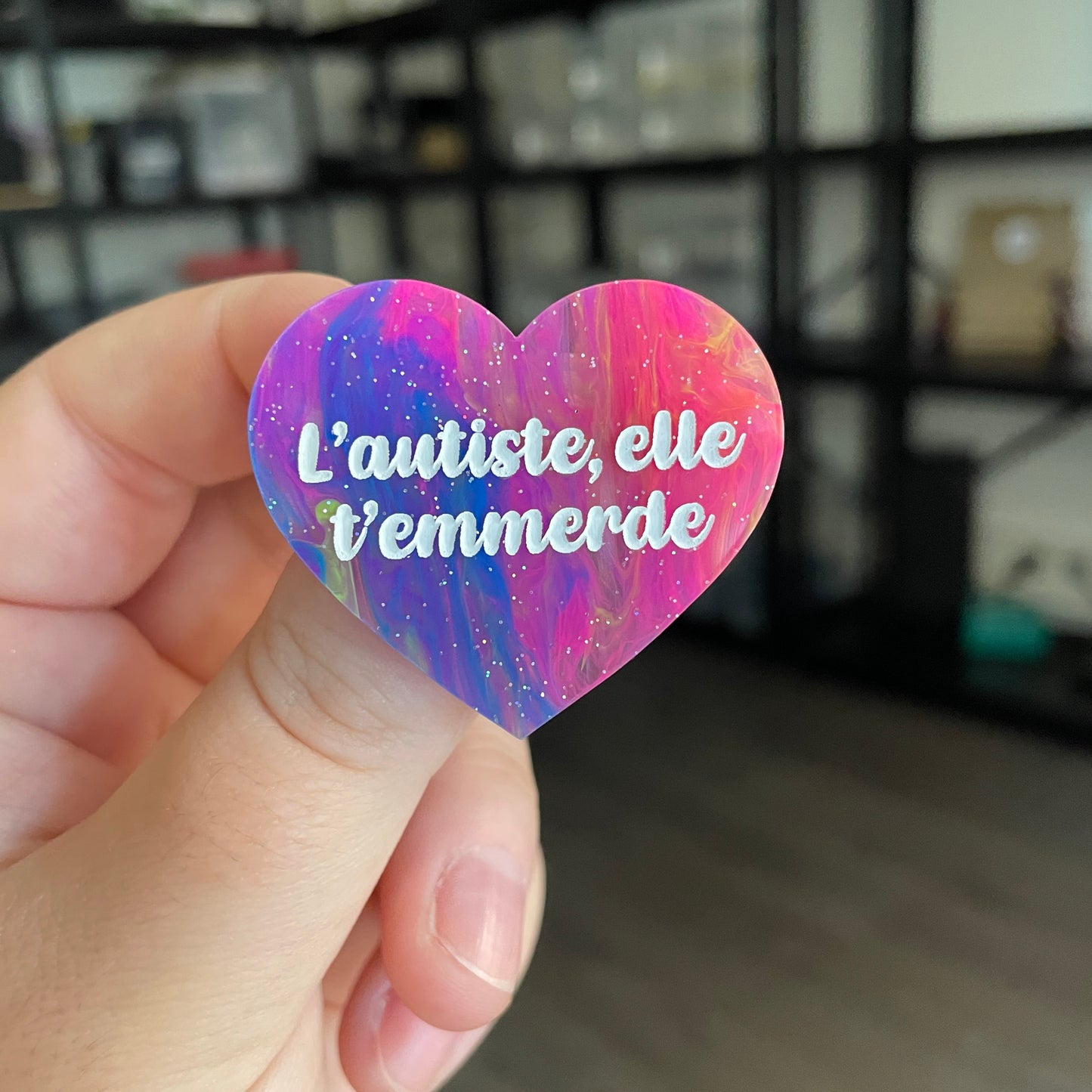 Broche "L'autiste, elle t'emmerde" en acrylique semi transparente marbrée multicolore