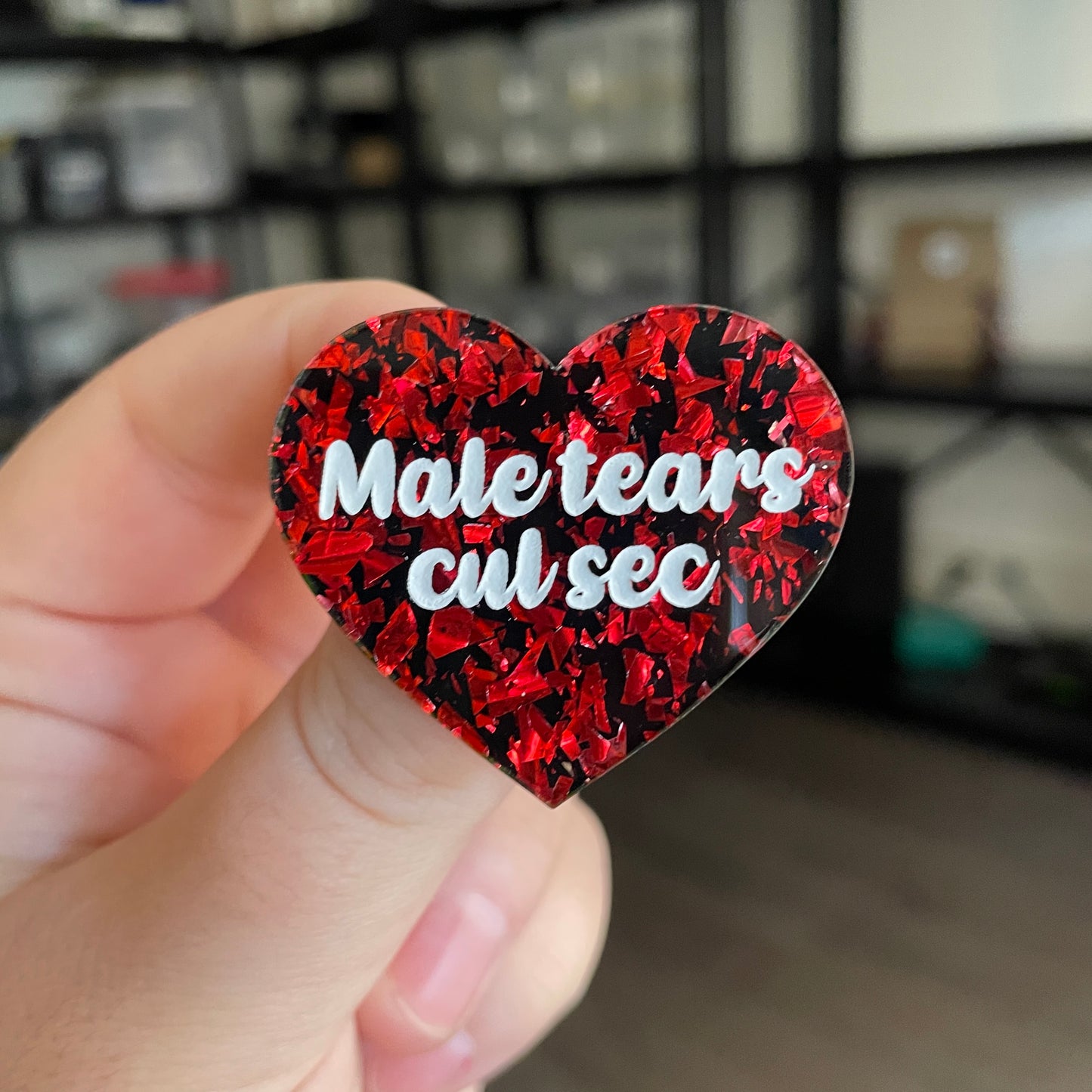 Broche "Male tears cul sec" en acrylique noire avec des éclats de confettis rouges