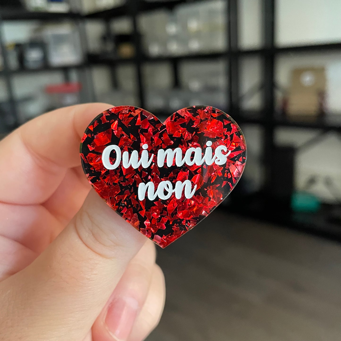 Broche "Oui mais non" en acrylique noire avec des éclats de confettis rouges