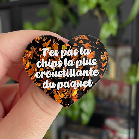 Broche "T'es pas la chips la plus croustillante du paquet" en acrylique noire avec des éclats de confettis oranges