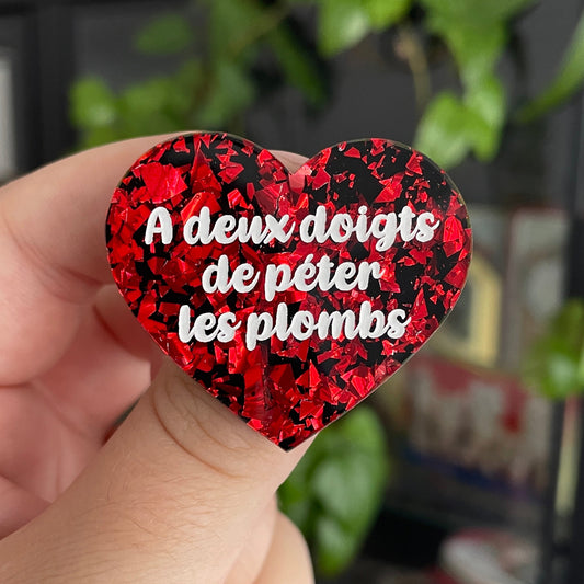 Broche "A deux doigts de péter les plombs" en acrylique noire avec des éclats de confettis rouges