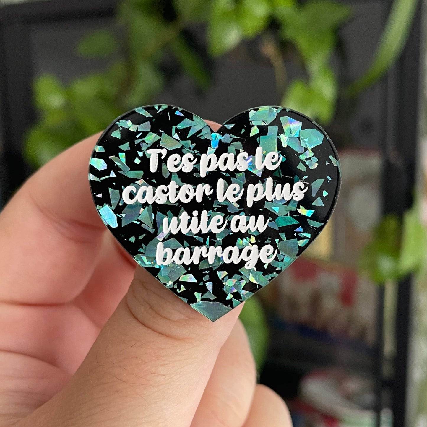 Broche "T'es pas le castor le plus utile au barrage" en acrylique noire avec des éclats de confettis turquoise