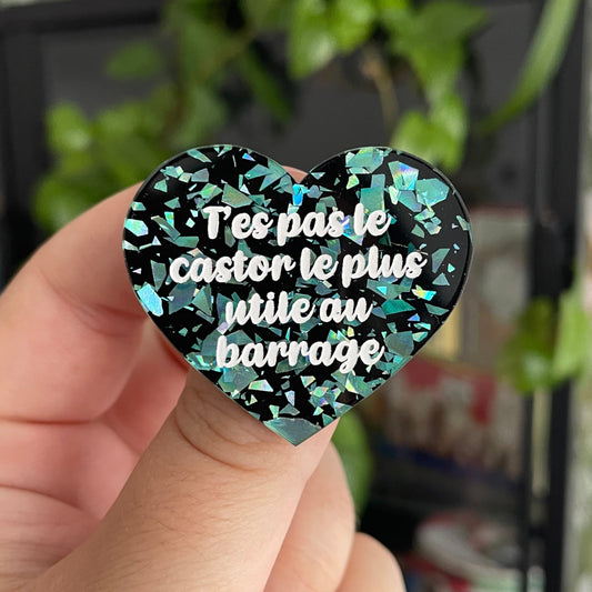 Broche "T'es pas le castor le plus utile au barrage" en acrylique noire avec des éclats de confettis turquoise