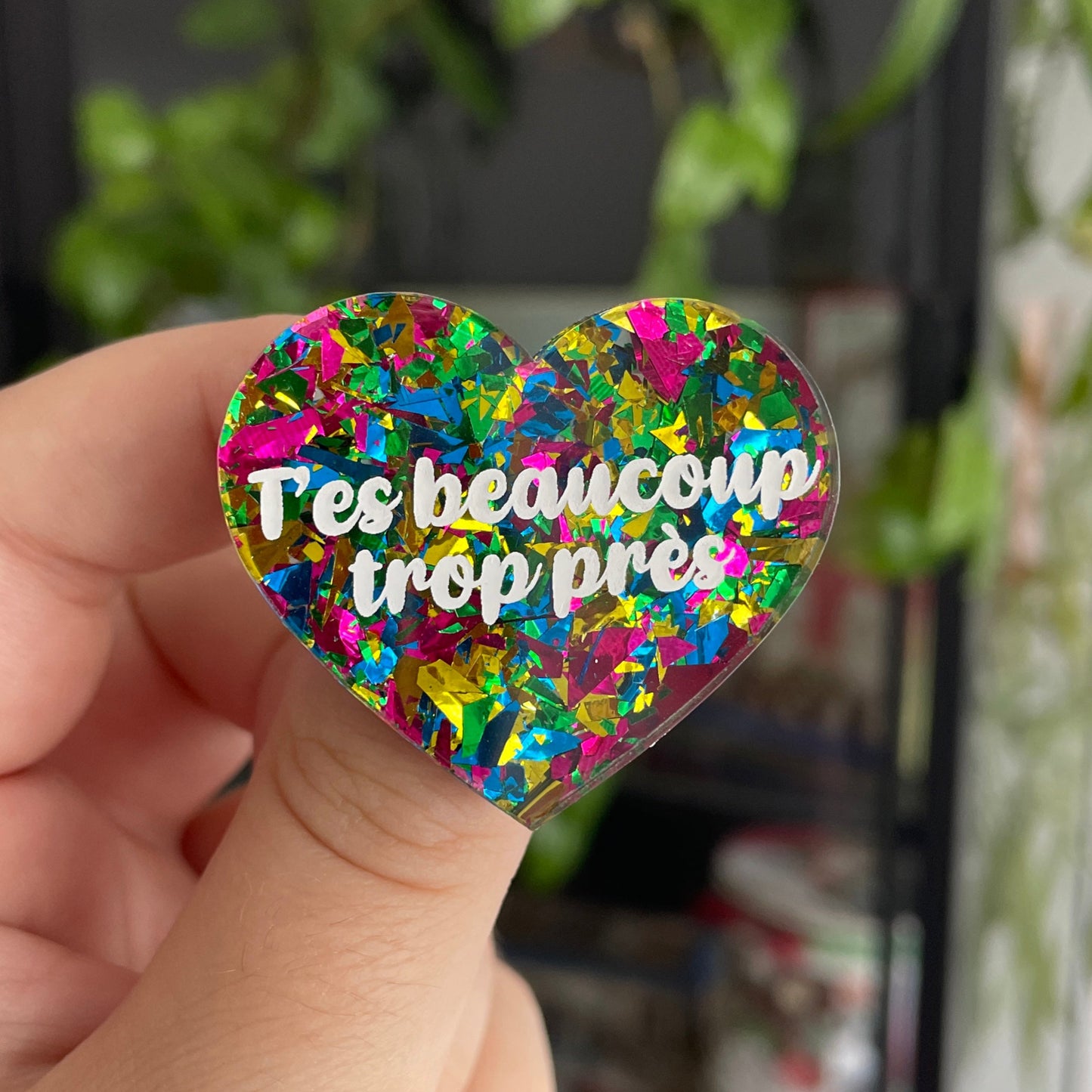 Broche "T'es beaucoup trop près" en acrylique transparente avec des éclats de confettis jaunes, verts, bleus et roses