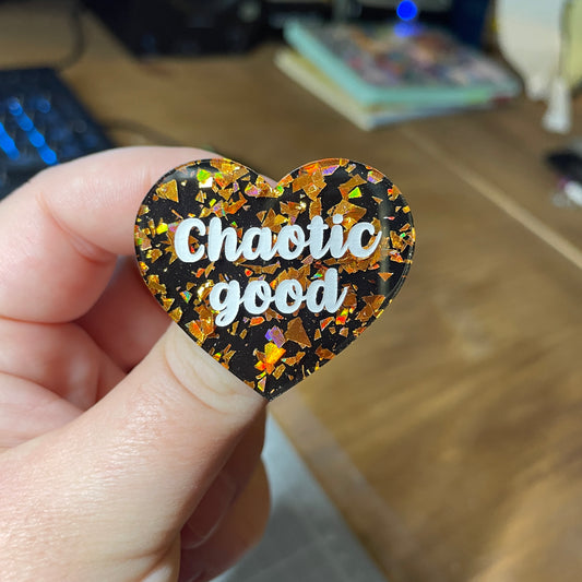 Broche "Chaotic good" en acrylique noire avec des éclats de confettis oranges