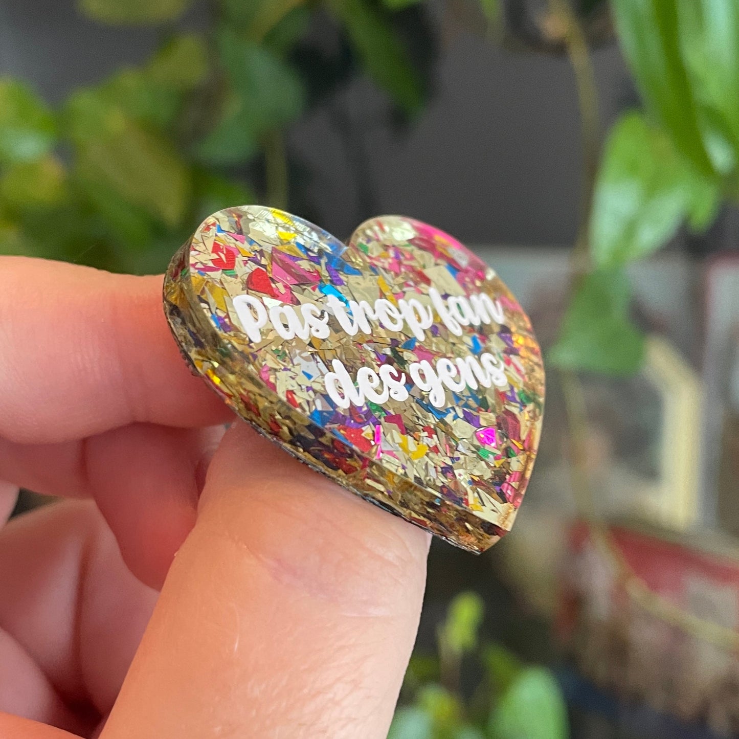 Broche "Pas trop fan des gens" en acrylique transparente avec des éclats de confettis dorés et multicolores
