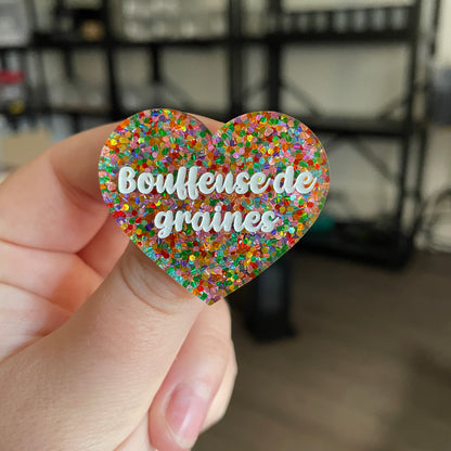 Broche "Bouffeuse de graines" en acrylique semi transparente avec des pois multicolores