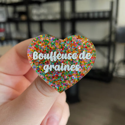 Broche "Bouffeuse de graines" en acrylique semi transparente avec des pois multicolores