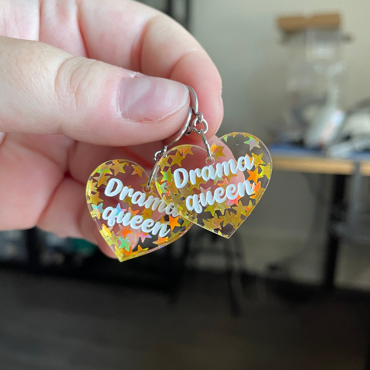 Petites boucles d'oreilles coeurs pendantes "Drama queen" en acrylique transparente avec des confettis étoiles dorées