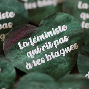 Broche "La féministe qui rit pas à tes blagues" en acrylique marbrée verte, noire et rose/violette