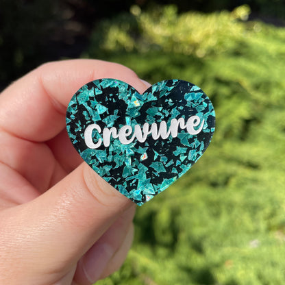 Broche "Crevure" en acrylique noire à confettis galactiques turquoise