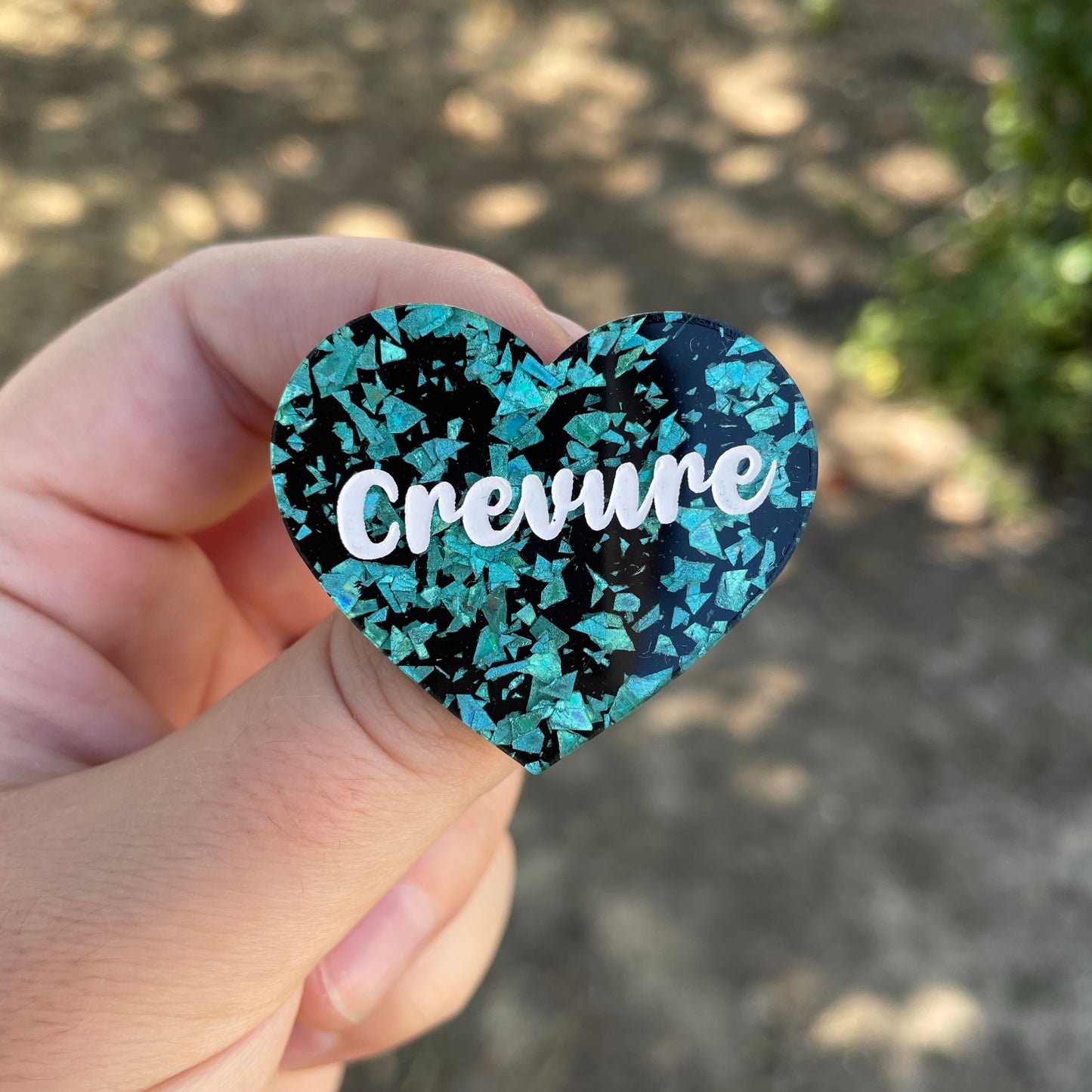 Broche "Crevure" en acrylique noire à confettis galactiques turquoise