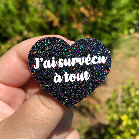 Broche "J'ai survécu à tout" en acrylique à paillettes noires holographiques