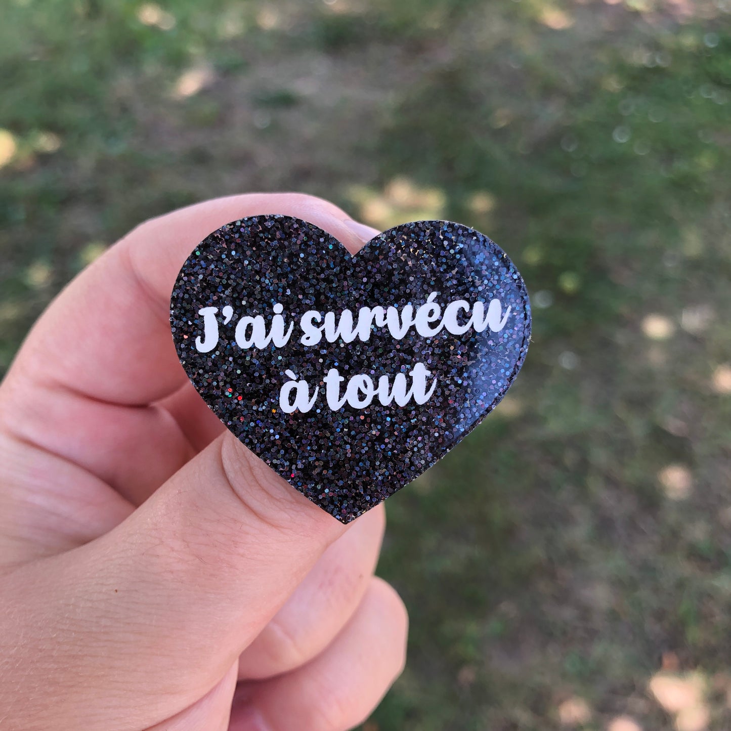 Broche "J'ai survécu à tout" en acrylique à paillettes noires holographiques