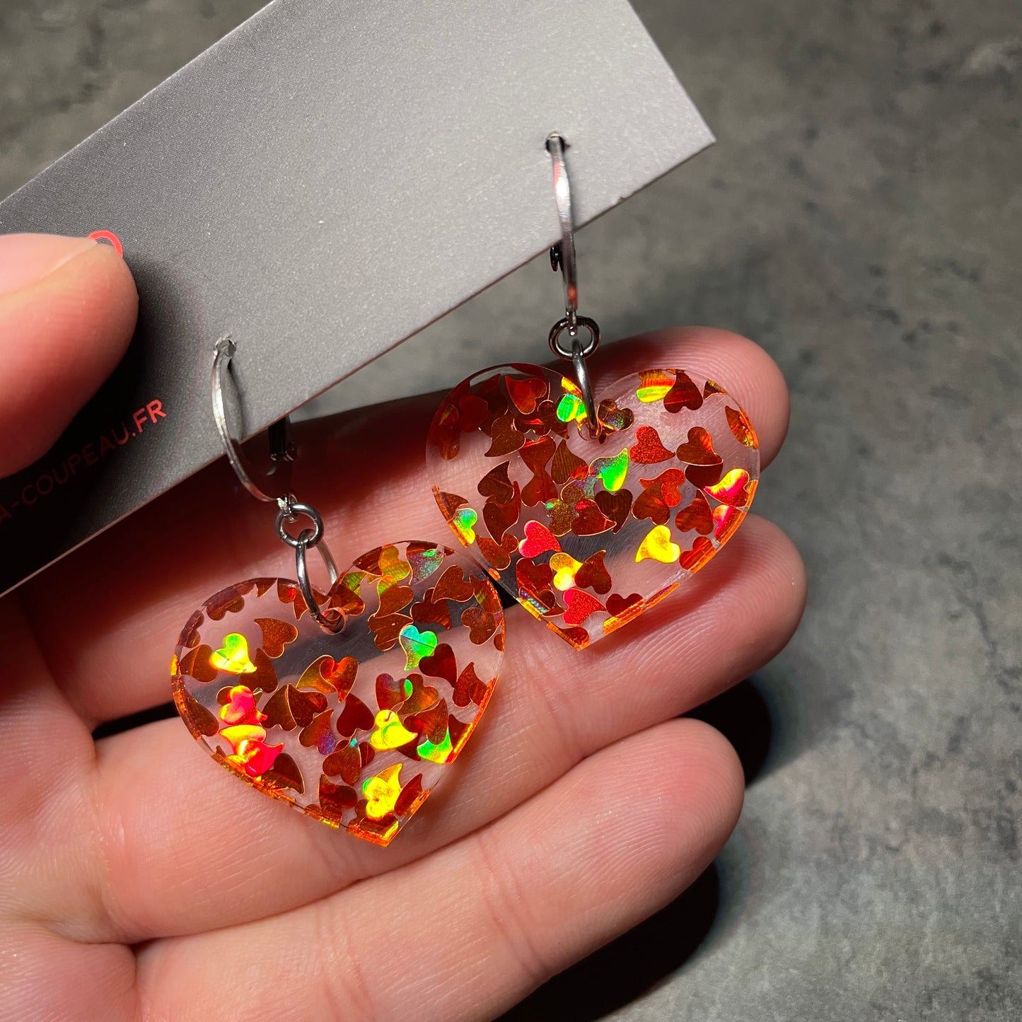 Petites boucles d'oreilles coeurs pendantes en acrylique transparente avec des confettis coeurs oranges holographiques