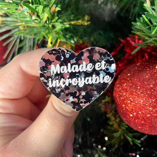 Broche "Malade et incroyable" en acrylique transparente à gros confettis noirs et argentés