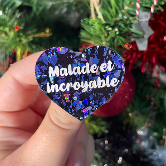 Broche "Malade et incroyable" en acrylique noire à confettis galactiques bleus