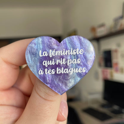 Broche "La féministe qui rit pas à tes blagues" en acrylique marbrée bleue et violette à paillettes