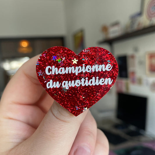 Broche "Championne du quotidien" en acrylique à paillettes rouges et étoiles holographiques