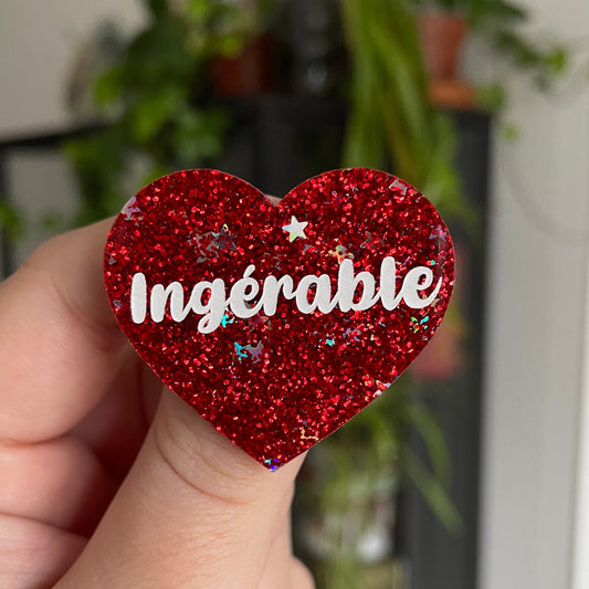 Broche "Ingérable" en acrylique rouge à paillettes avec des étoiles