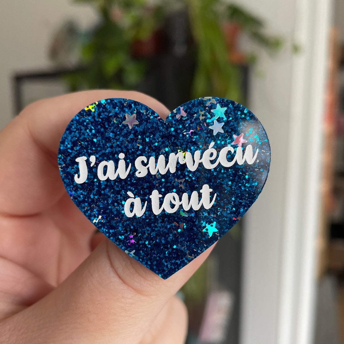 Broche "J'ai survécu à tout" en acrylique bleue à paillettes avec des étoiles