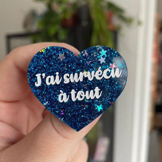 Broche "J'ai survécu à tout" en acrylique bleue à paillettes avec des étoiles