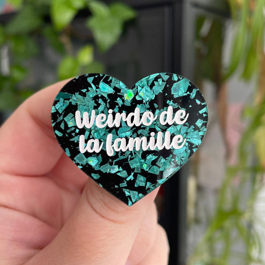 Broche "Weirdo de la famille" en acrylique noire à confettis galactiques turquoise