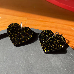Petites boucles d'oreilles coeurs pendantes en acrylique noire avec des paillettes dorées