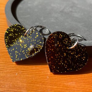 Petites boucles d'oreilles coeurs pendantes en acrylique noire avec des paillettes dorées