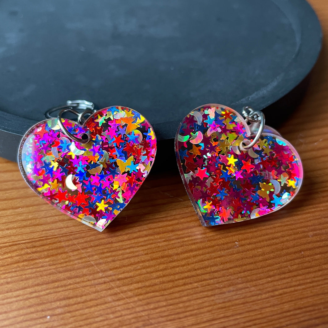 Petites boucles d'oreilles coeurs pendantes en acrylique avec des confettis étoiles et lunes multicolores