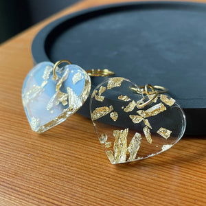 Petites boucles d'oreilles coeurs pendantes en acrylique transparente avec des éclats de feuilles dorées