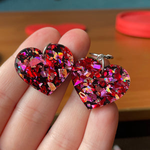 Petites boucles d'oreilles coeurs pendantes en acrylique noire avec des confettis galactiques rouges et roses