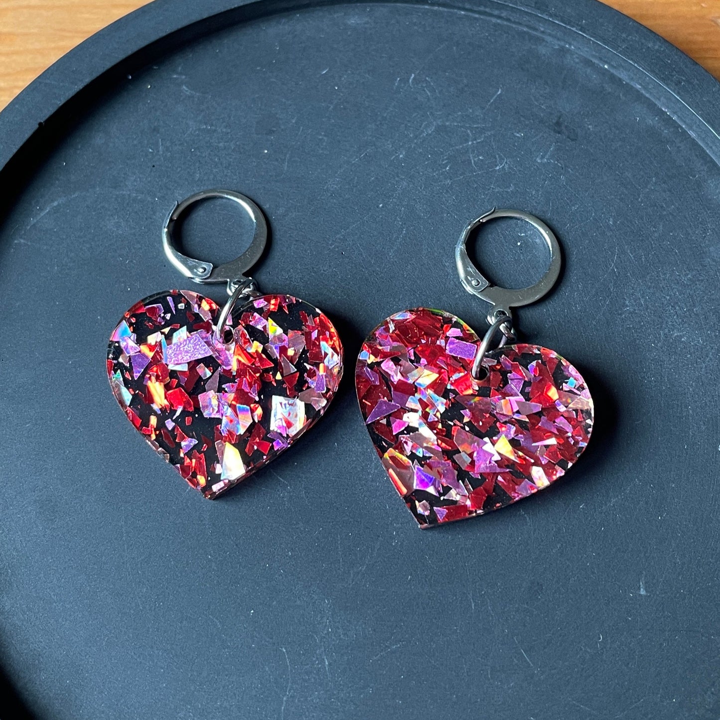 Petites boucles d'oreilles coeurs pendantes en acrylique noire avec des confettis galactiques rouges et roses