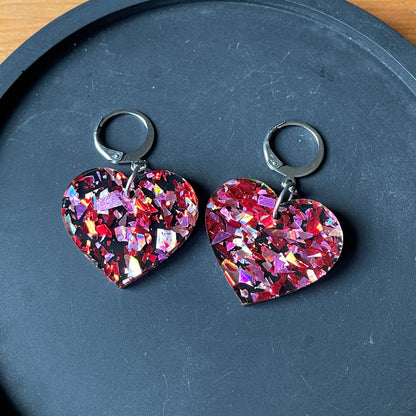 Petites boucles d'oreilles coeurs pendantes en acrylique noire avec des confettis galactiques rouges et roses