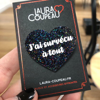 Broche "J'ai survécu à tout" en acrylique à paillettes noires holographiques