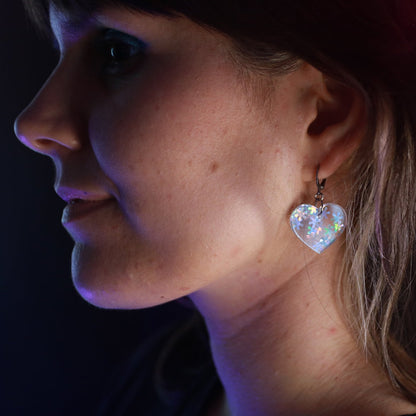 Petites boucles d'oreilles coeurs pendantes en acrylique transparente avec des confettis flocons holographiques