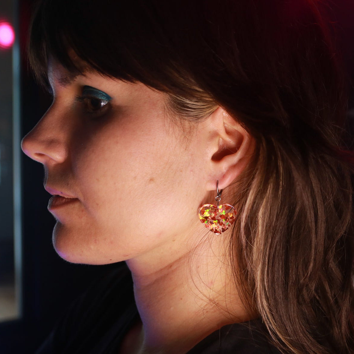 Petites boucles d'oreilles coeurs pendantes en acrylique transparente avec des confettis coeurs oranges holographiques
